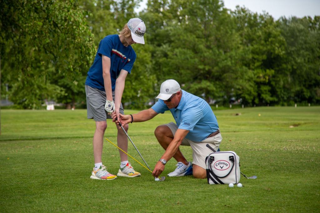 instructor teaching a high school student golfer
