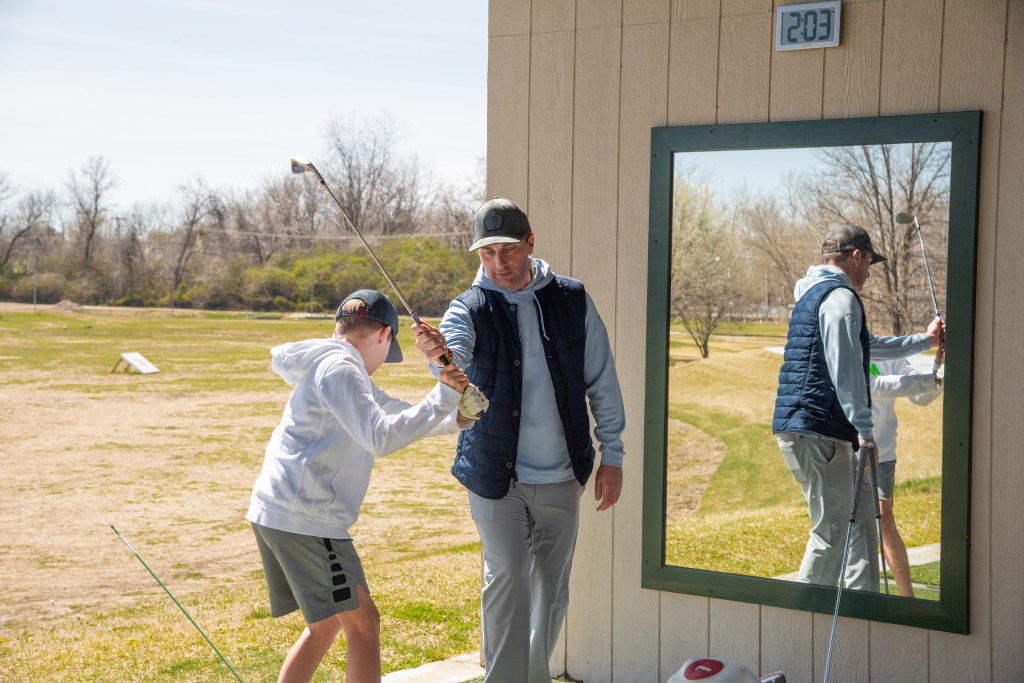 Golf instructor teaching child to hold club at angle