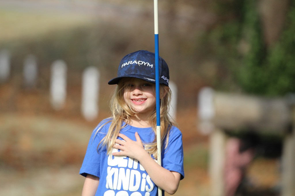 Little girl in baseball hat and blue t-shirt on golf course