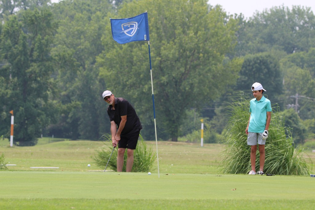Little boy and old man playing golf with family golf flag